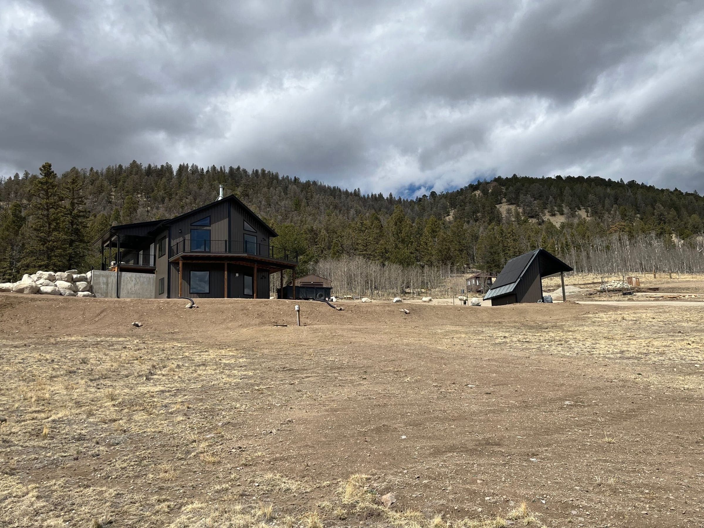 Finished house and outbuilding under dramatic cloudy sky