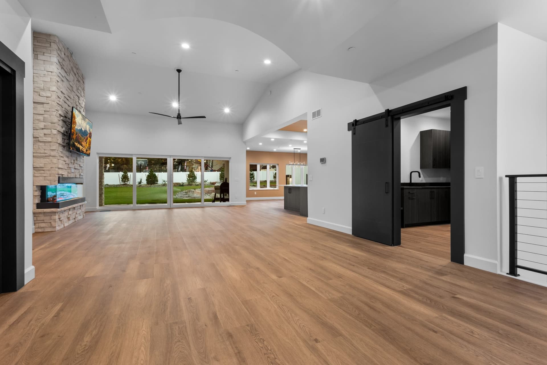 Dining area — terracotta accent wall, contemporary black linear chandelier, large windows to landscaped backyard