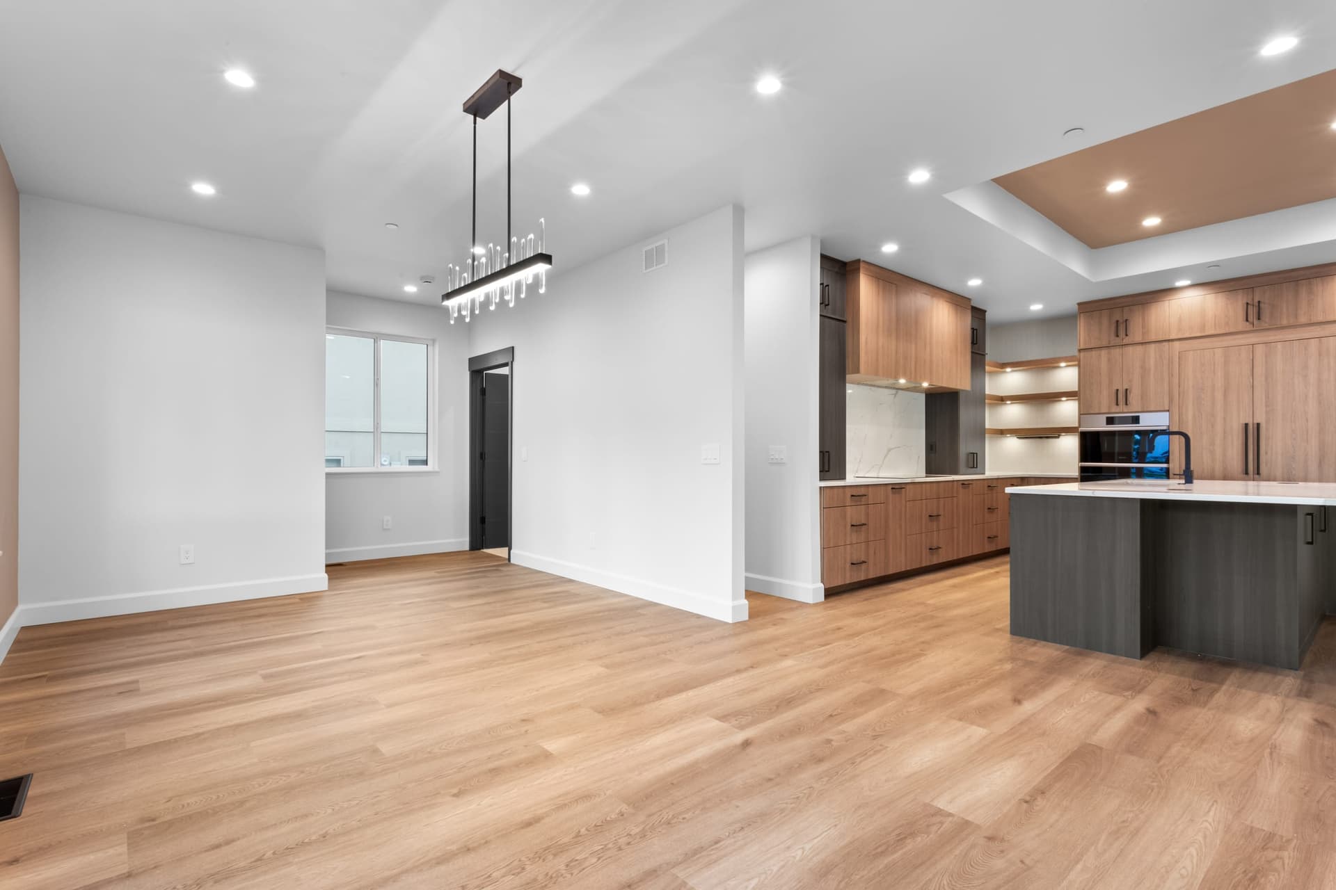 Kitchen and adjacent dining with walnut cabinetry, white quartz island, and linear chandelier