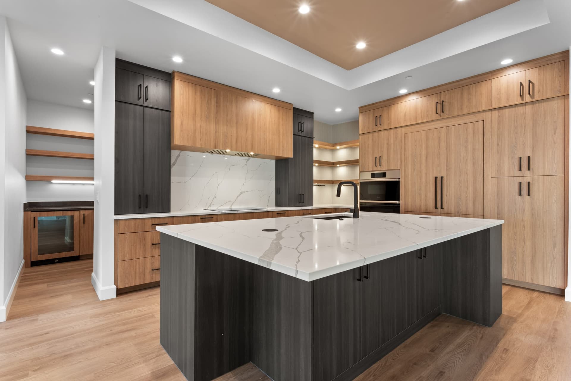Island sink detail — white quartz waterfall countertop, matte black faucet, integrated pop-up electrical outlets
