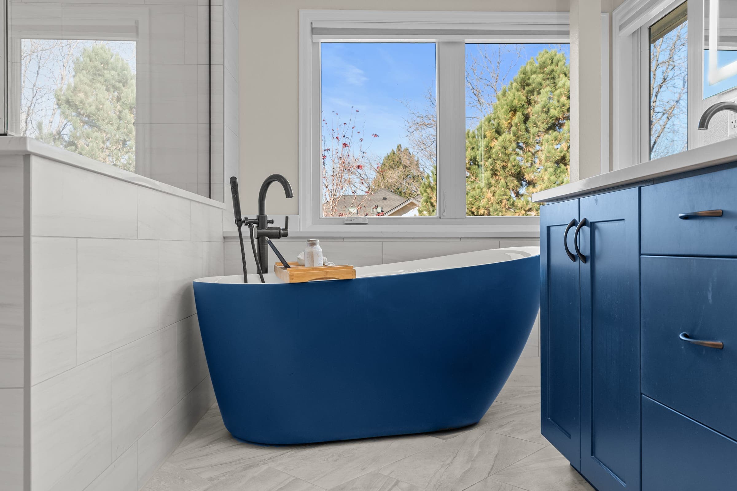 Bathroom soaking tub and blue cabinetry by Kiefer Built Contracting