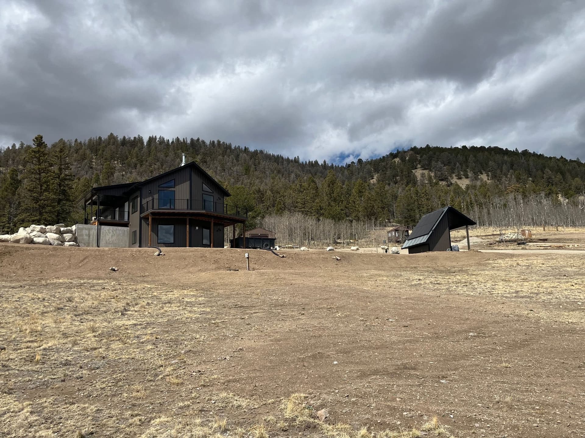 Finished house and outbuilding under dramatic cloudy sky