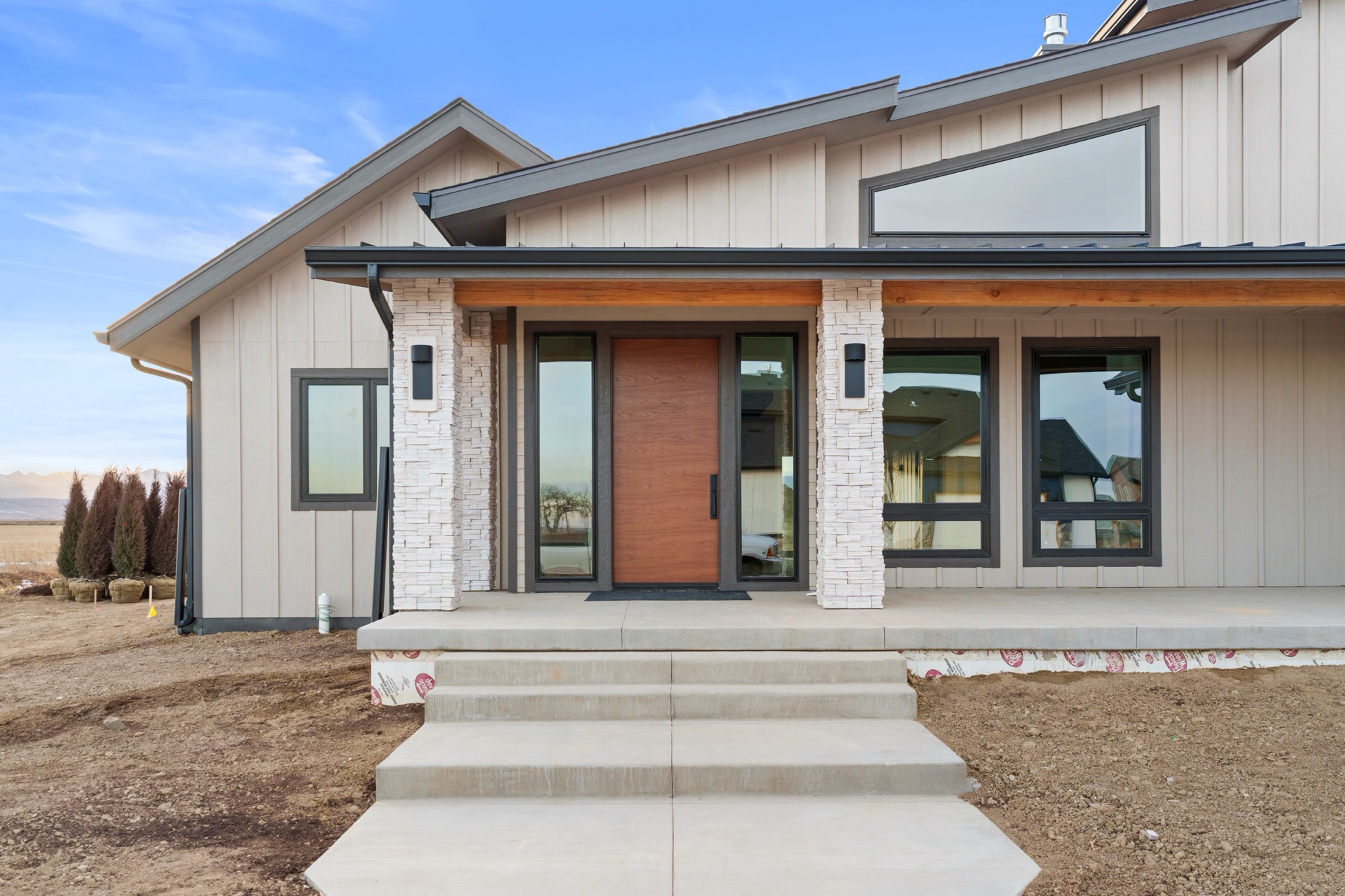 Custom walnut front entry door with stone pillar columns — built by Kiefer Built Contracting in Windsor, Colorado
